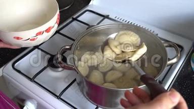 厨房里的一个女人在煤气灶旁边的一个锅里煮饺子